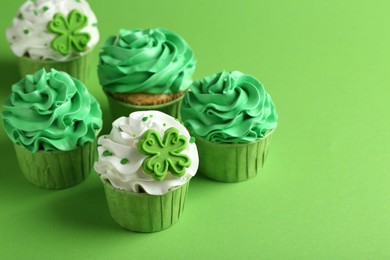 St. Patrick's day party. Tasty festively decorated cupcakes on green background, closeup. Space for text