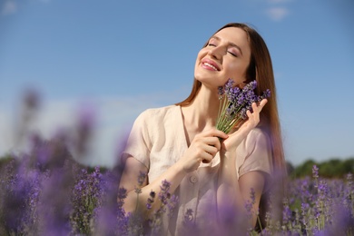 Young woman with lavender bouquet in field on summer day