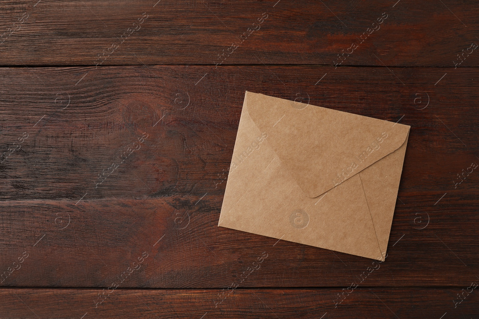 Photo of Brown paper envelope on wooden table, top view. Space for text