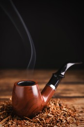 Photo of Smoking pipe with tobacco on wooden table