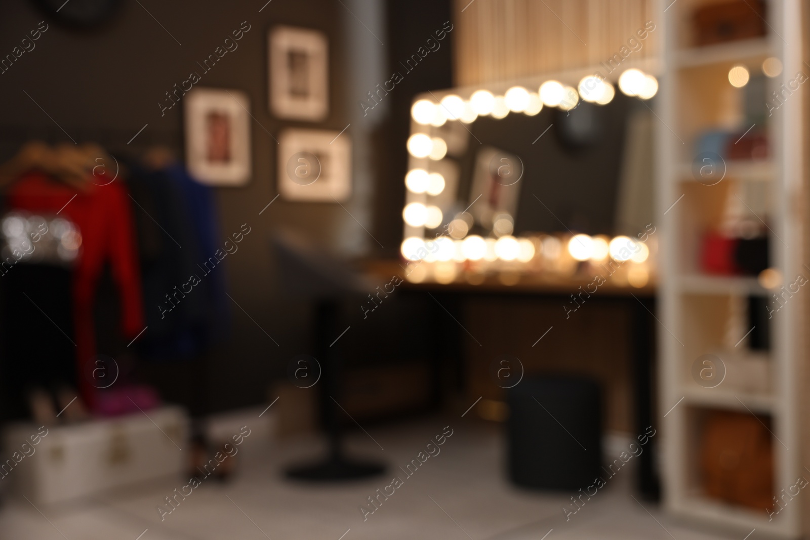 Photo of Blurred view of makeup room with stylish mirror on dressing table, chair and clothes rack