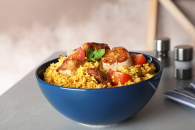 Photo of Bowl with delicious rice pilaf served on table