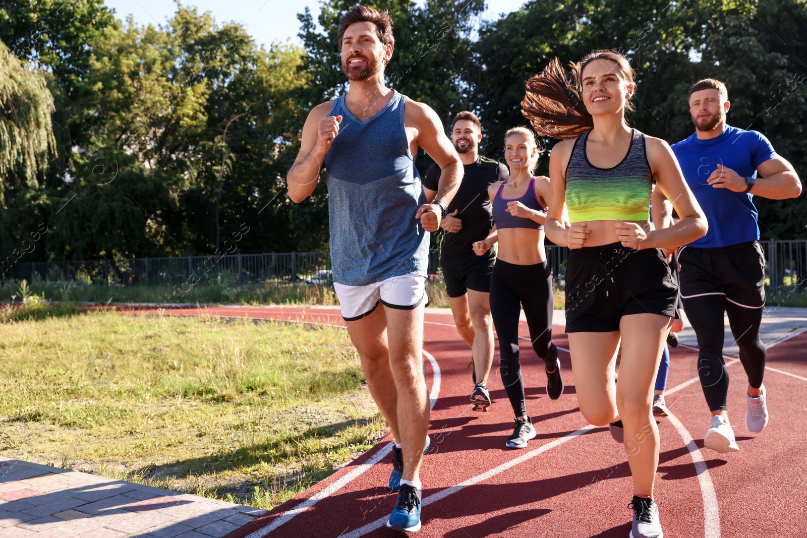 Photo of Group of people running at stadium on sunny day