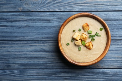 Photo of Bowl of fresh homemade mushroom soup on wooden background, top view with space for text