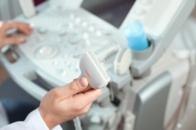 Sonographer holding ultrasound machine probe in clinic, closeup with space for text