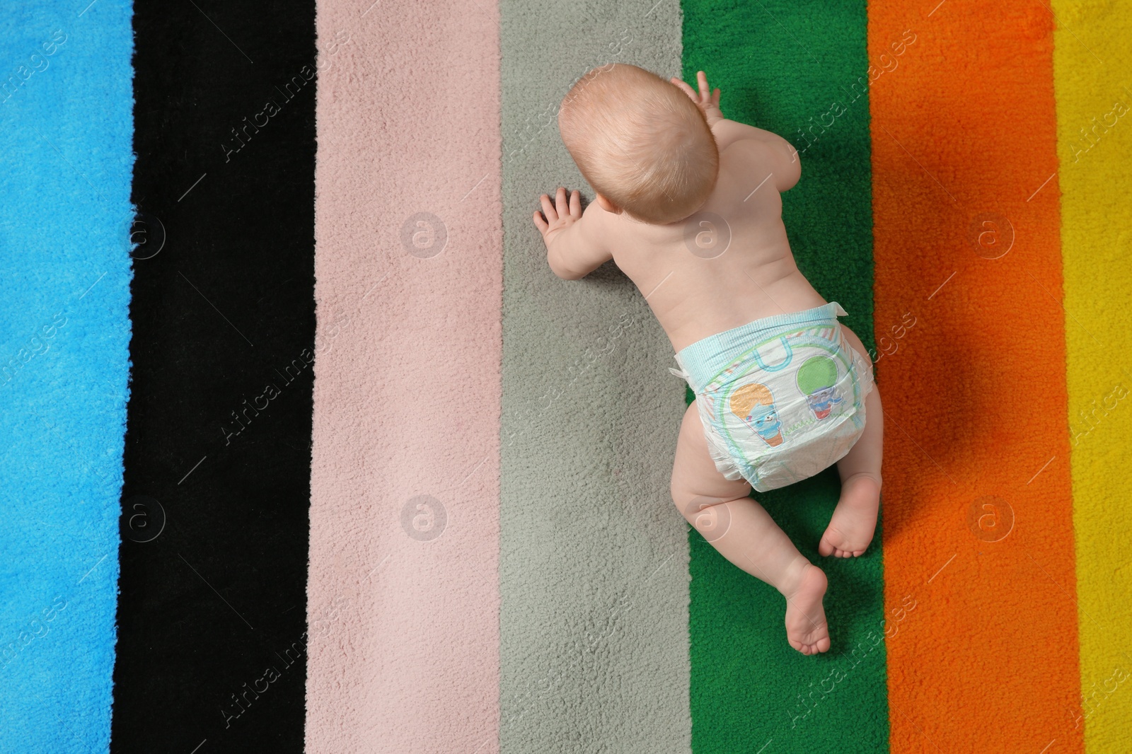 Photo of Cute little baby crawling on colorful carpet indoors, top view with space for text