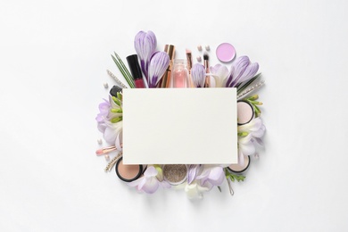 Makeup products, spring flowers and blank card on white background, top view. Space for text