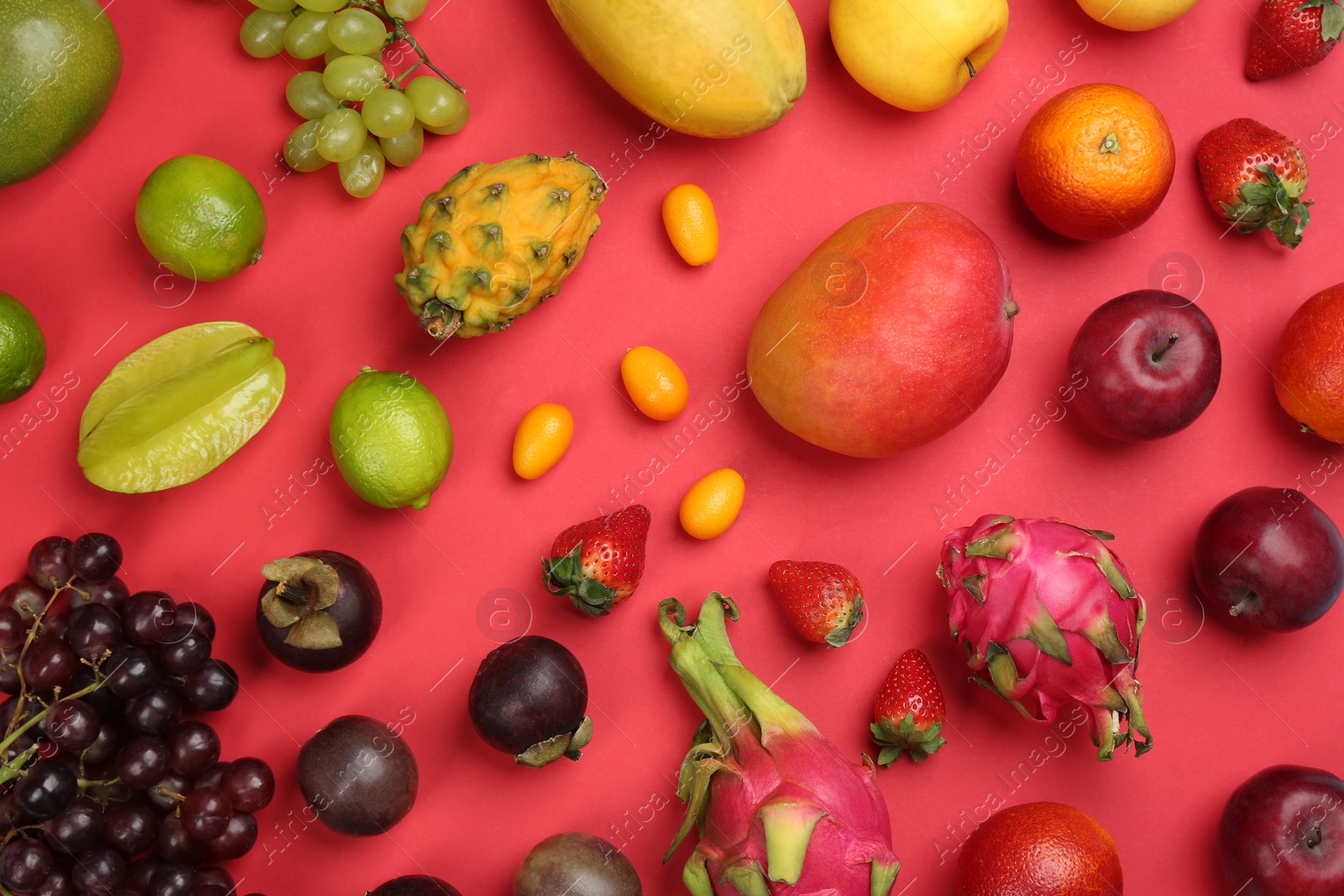 Photo of Many different delicious exotic fruits on red background, flat lay