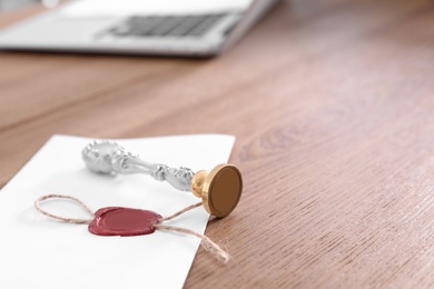 Photo of Sealed document and vintage notary stamp on table with space for text, closeup