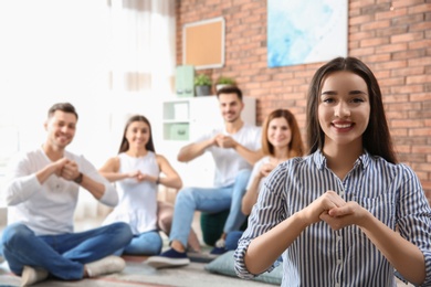 Young teacher showing sign language gesture against blurred background