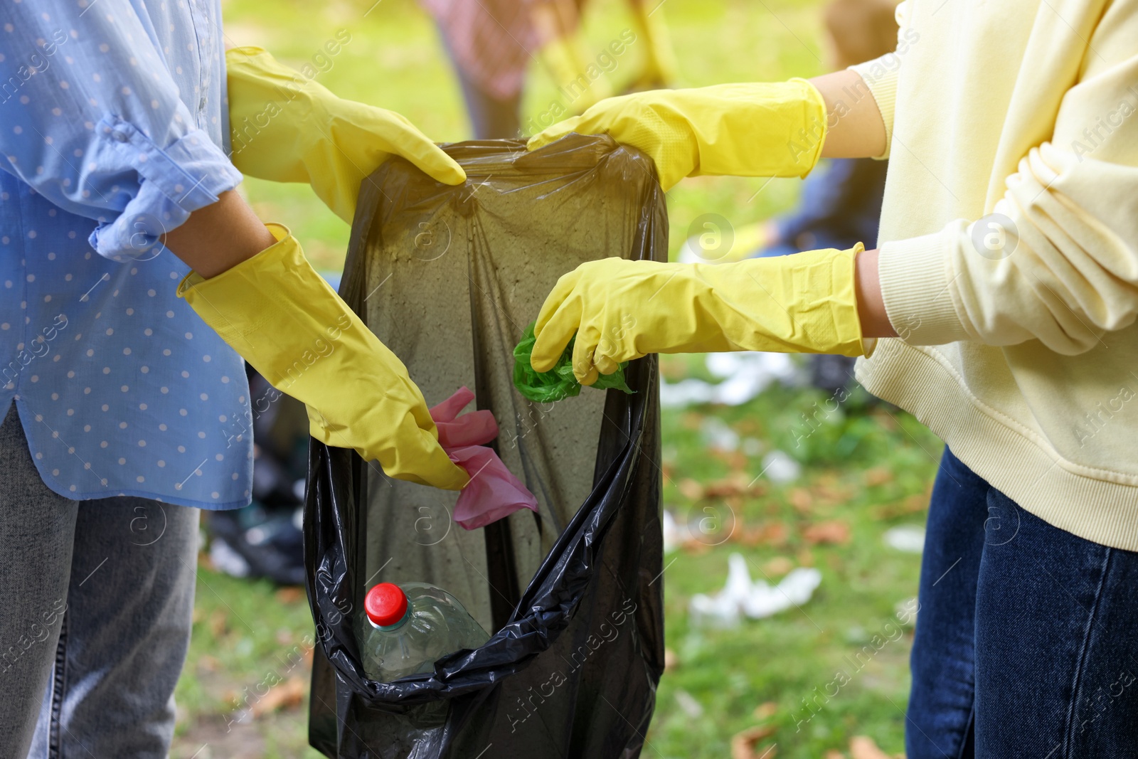 Photo of Women with plastic bag collecting garbage in park, closeup