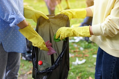 Photo of Women with plastic bag collecting garbage in park, closeup