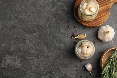 Photo of Flat lay composition with jars of pickled garlic on grey table. Space for text