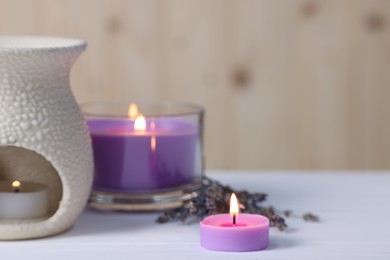 Photo of Aromatherapy. Burning candles on white wooden table, closeup. Space for text