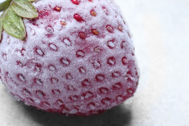Photo of One frozen ripe strawberry on light table, closeup