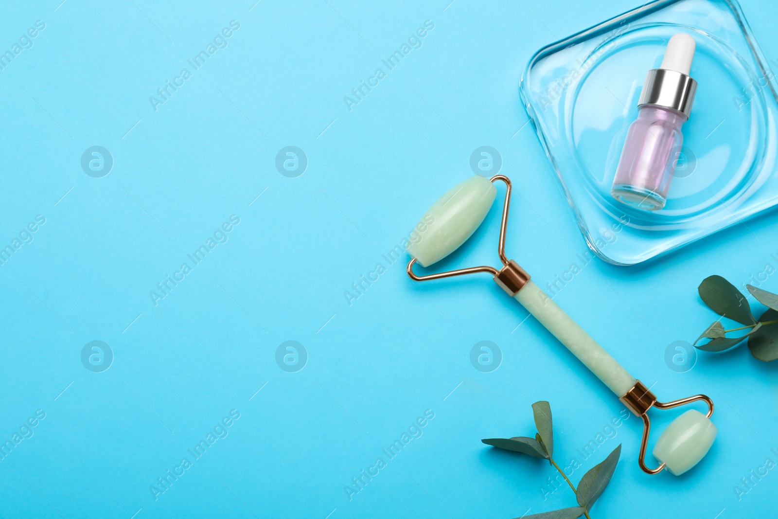 Photo of Natural face roller, cosmetic product and eucalyptus on light blue background, flat lay. Space for text