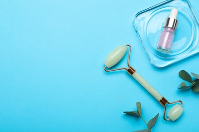 Natural face roller, cosmetic product and eucalyptus on light blue background, flat lay. Space for text