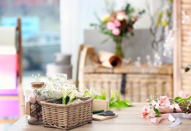 Photo of Decorator's workplace with beautiful flowers and unfinished wreath on table