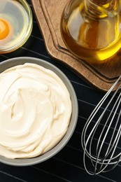 Photo of Bowl with fresh mayonnaise and ingredients on napkin, flat lay