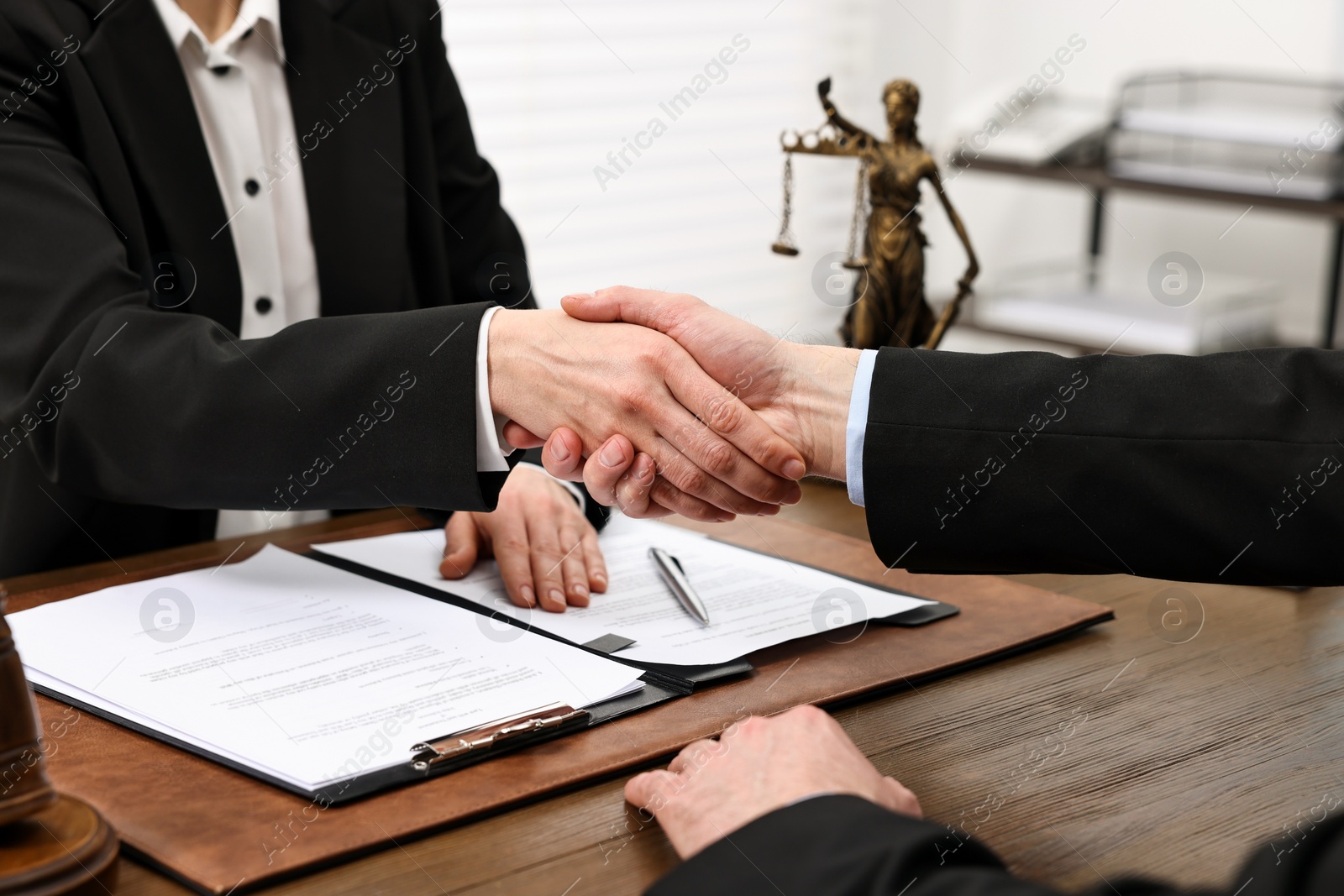 Photo of Lawyer shaking hands with client in office, closeup