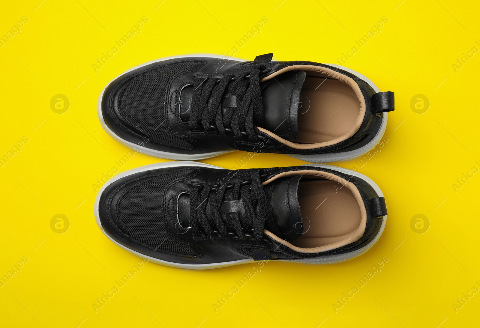 Photo of Pair of stylish shoes on yellow background, top view