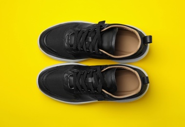 Photo of Pair of stylish shoes on yellow background, top view