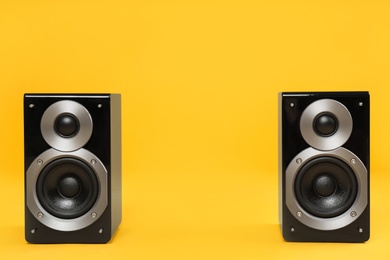 Modern powerful audio speakers on yellow background, space for text
