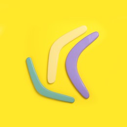 Photo of Colorful wooden boomerangs on yellow background, flat lay. Space for text