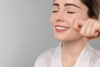 Photo of Young woman massaging her face on grey background. Space for text