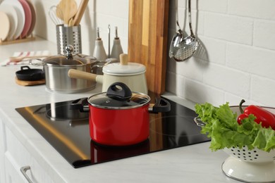 Photo of Red pot on electric stove in kitchen. Cooking utensil