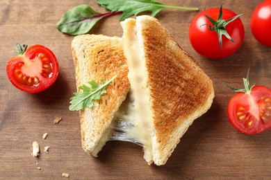 Image of Tasty toast sandwiches with cheese and tomatoes on wooden board