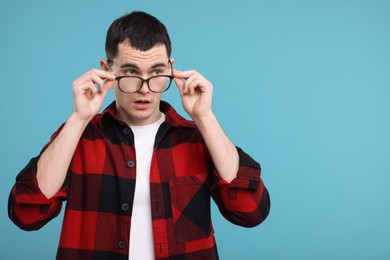 Photo of Surprised man in glasses on light blue background, space for text