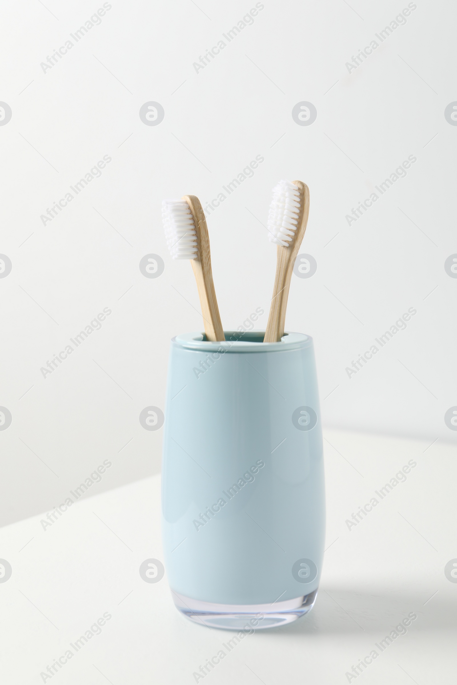 Photo of Bamboo toothbrushes in holder on white table