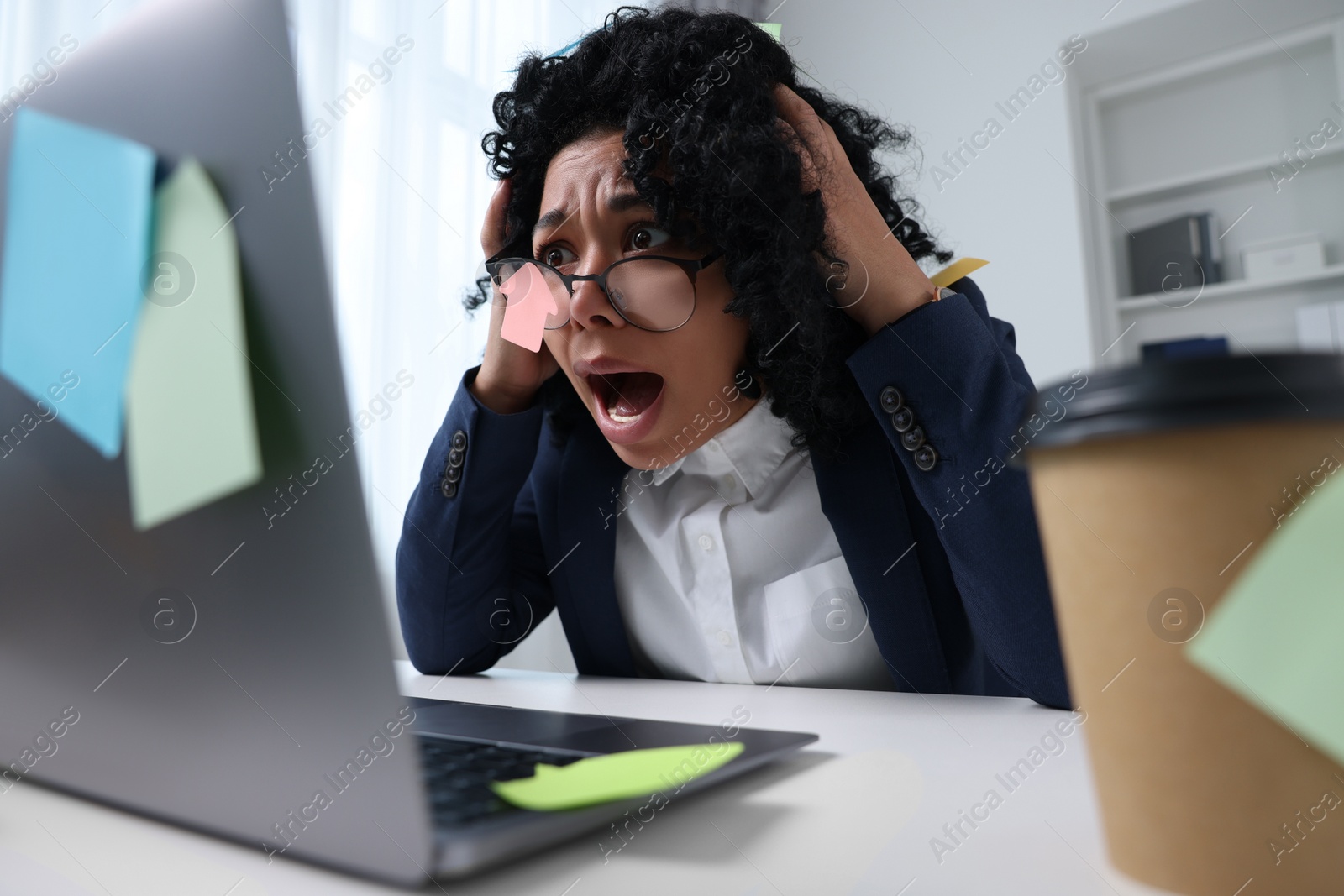 Photo of Deadline concept. Stressed woman looking at laptop and shouting in office. Many sticky notes everywhere as reminders