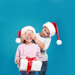 Image of Boy presenting Christmas gift to girl on light blue background