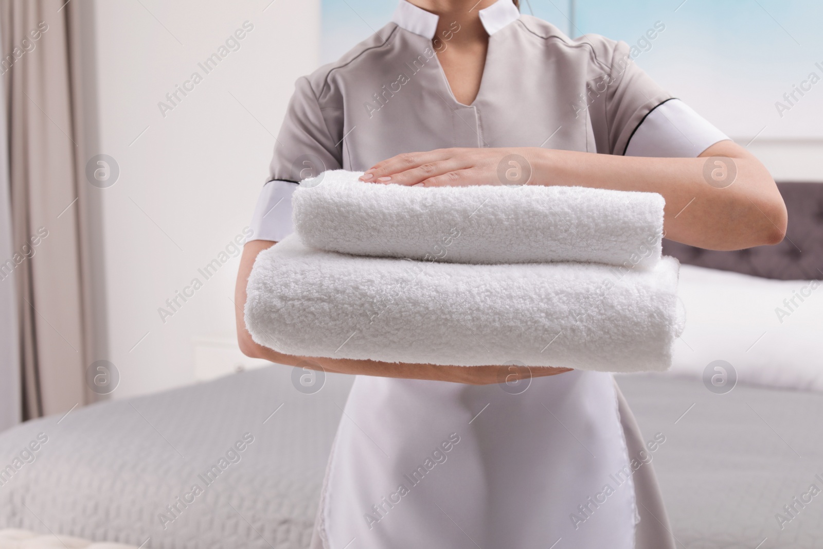 Photo of Maid with fresh towels in hotel room, closeup