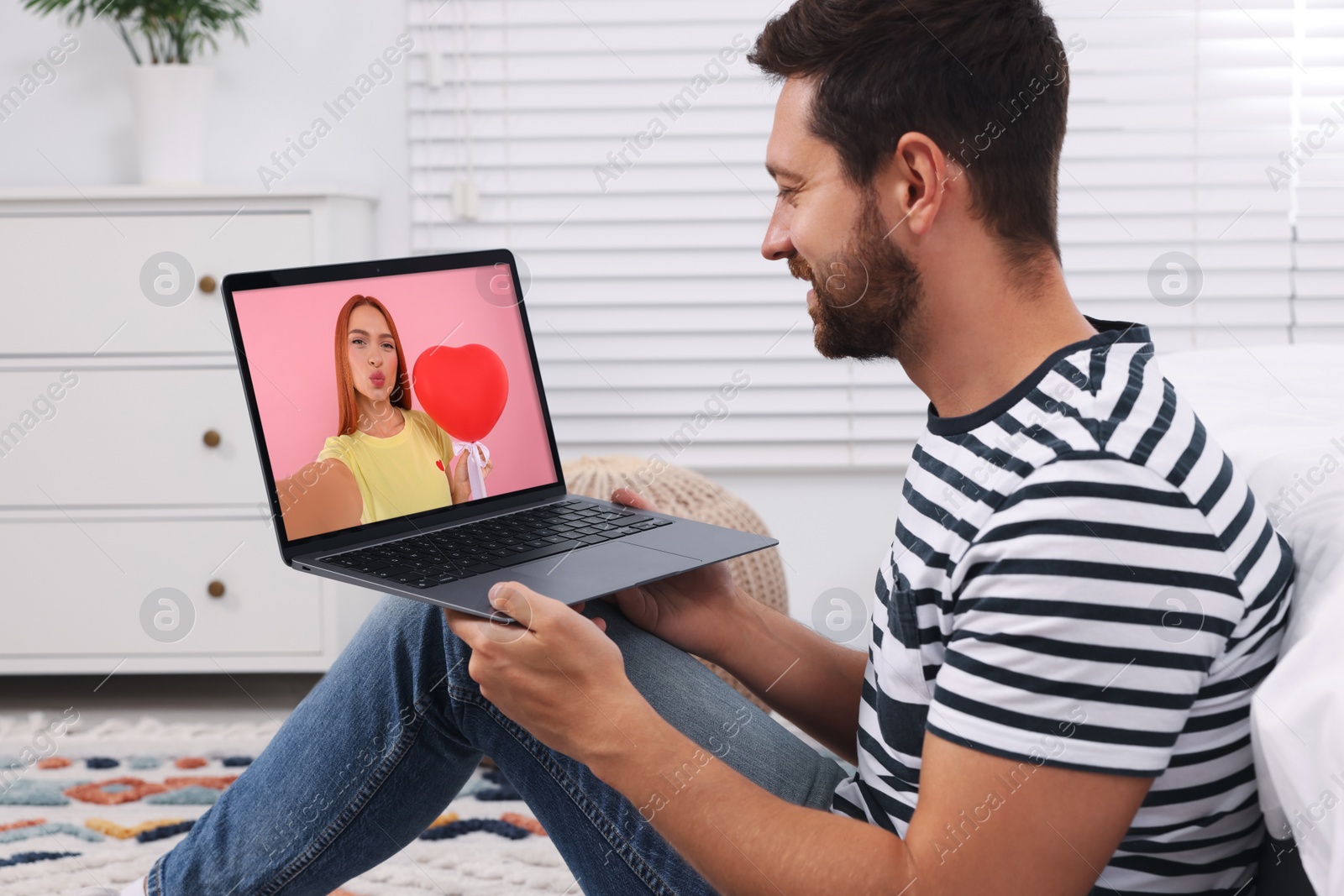 Image of Long distance love. Man having video chat with his girlfriend via laptop at home