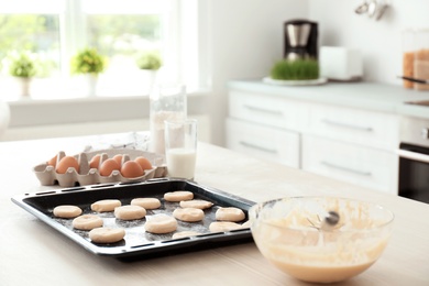 Products and baking tray with cookie dough on kitchen table