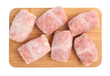 Wooden board with uncooked stuffed cabbage rolls on white background, top view