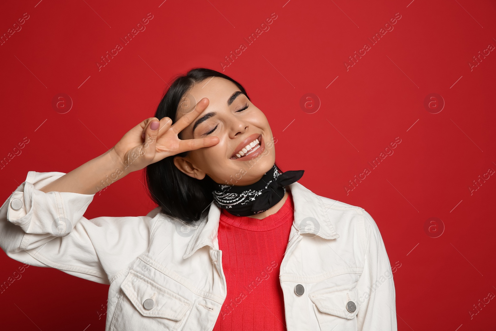 Photo of Fashionable young woman in stylish outfit with bandana on red background