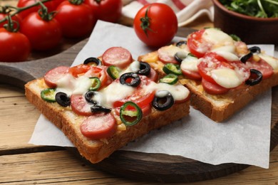 Tasty pizza toasts and tomatoes on wooden table, closeup