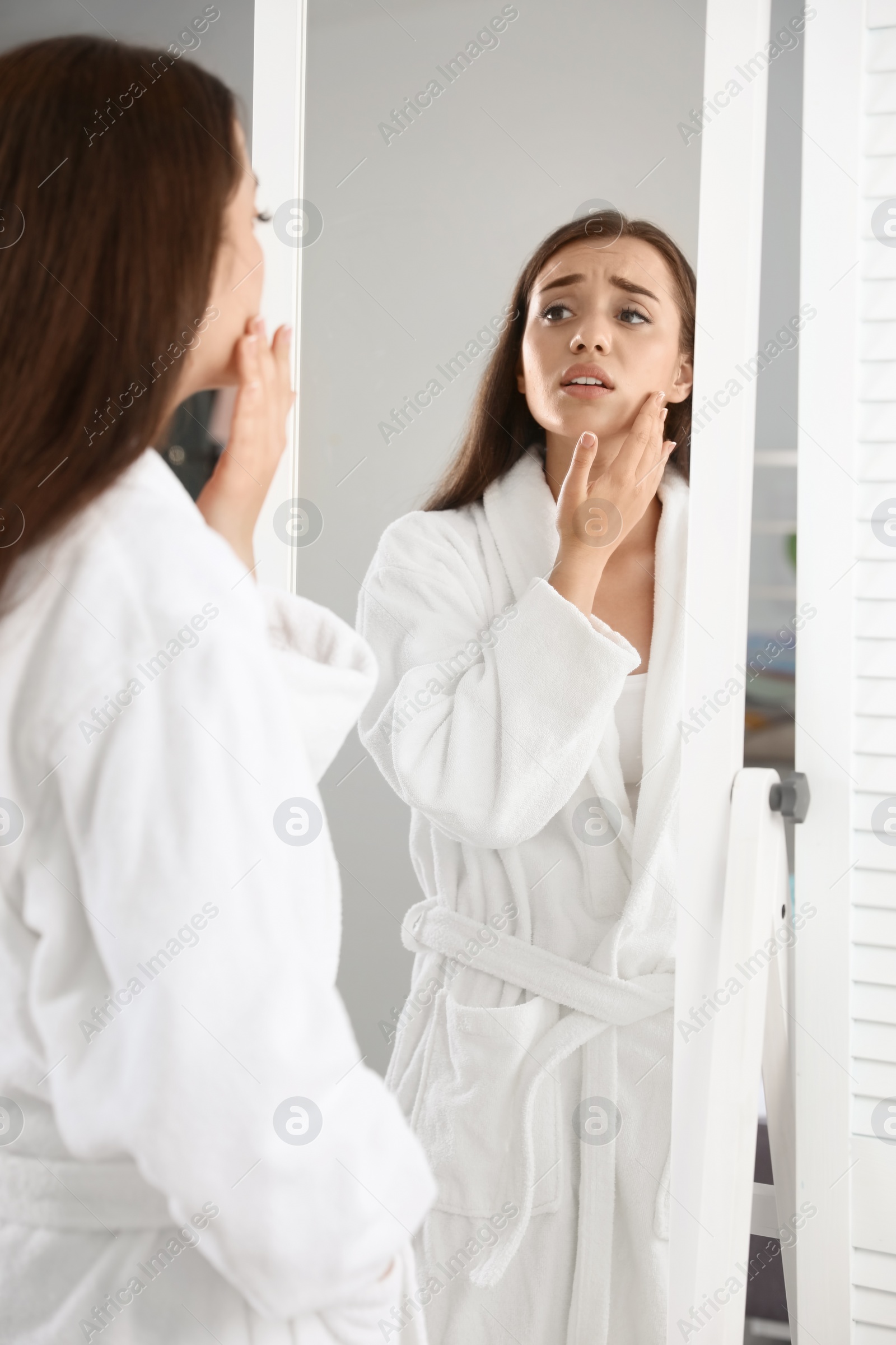 Photo of Emotional woman with beautiful eyelashes looking in mirror indoors