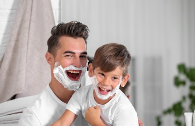 Photo of Father and son having fun while shaving in bathroom