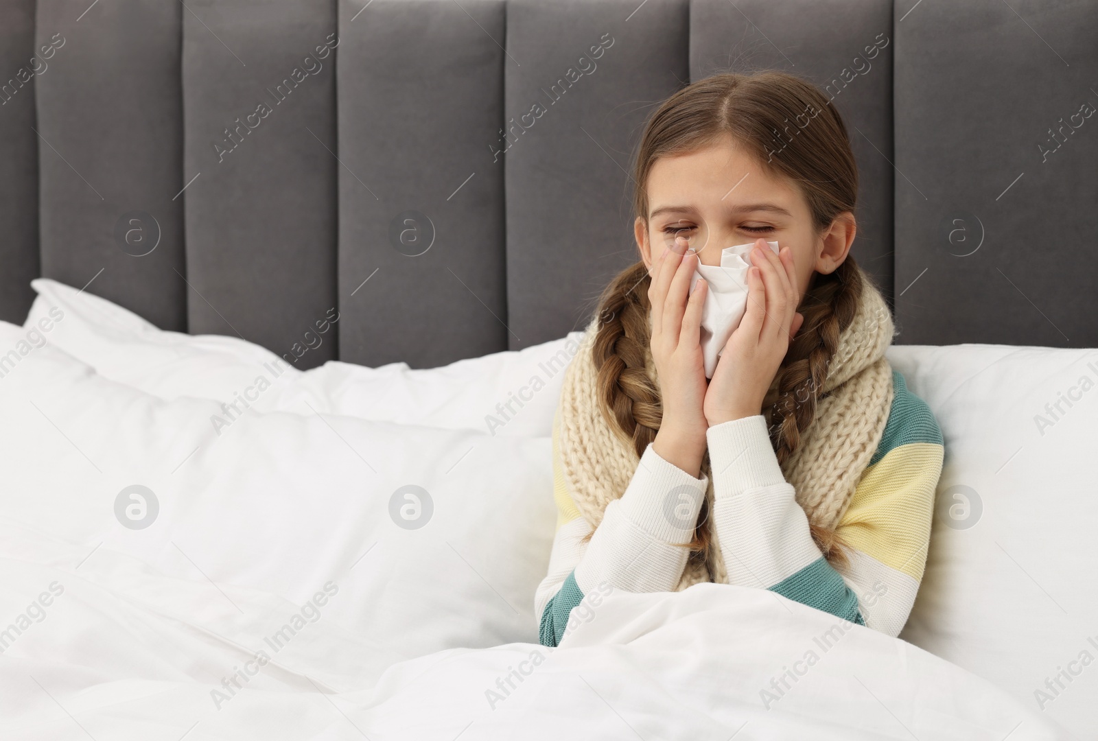 Photo of Sick girl with tissue coughing on bed at home