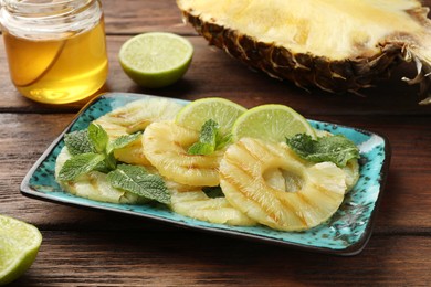 Tasty grilled pineapple slices, cut lime and honey on wooden table