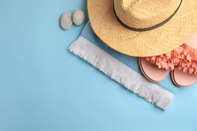 Flat lay composition with beach accessories on light blue background, space for text