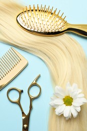 Photo of Flat lay composition with professional hairdresser tools, flower and blonde hair strand on light blue background