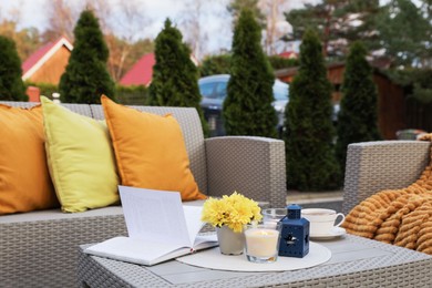 Beautiful rattan garden furniture, soft pillows and different decor elements in backyard