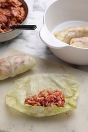Photo of Preparing stuffed cabbage rolls on white marble table