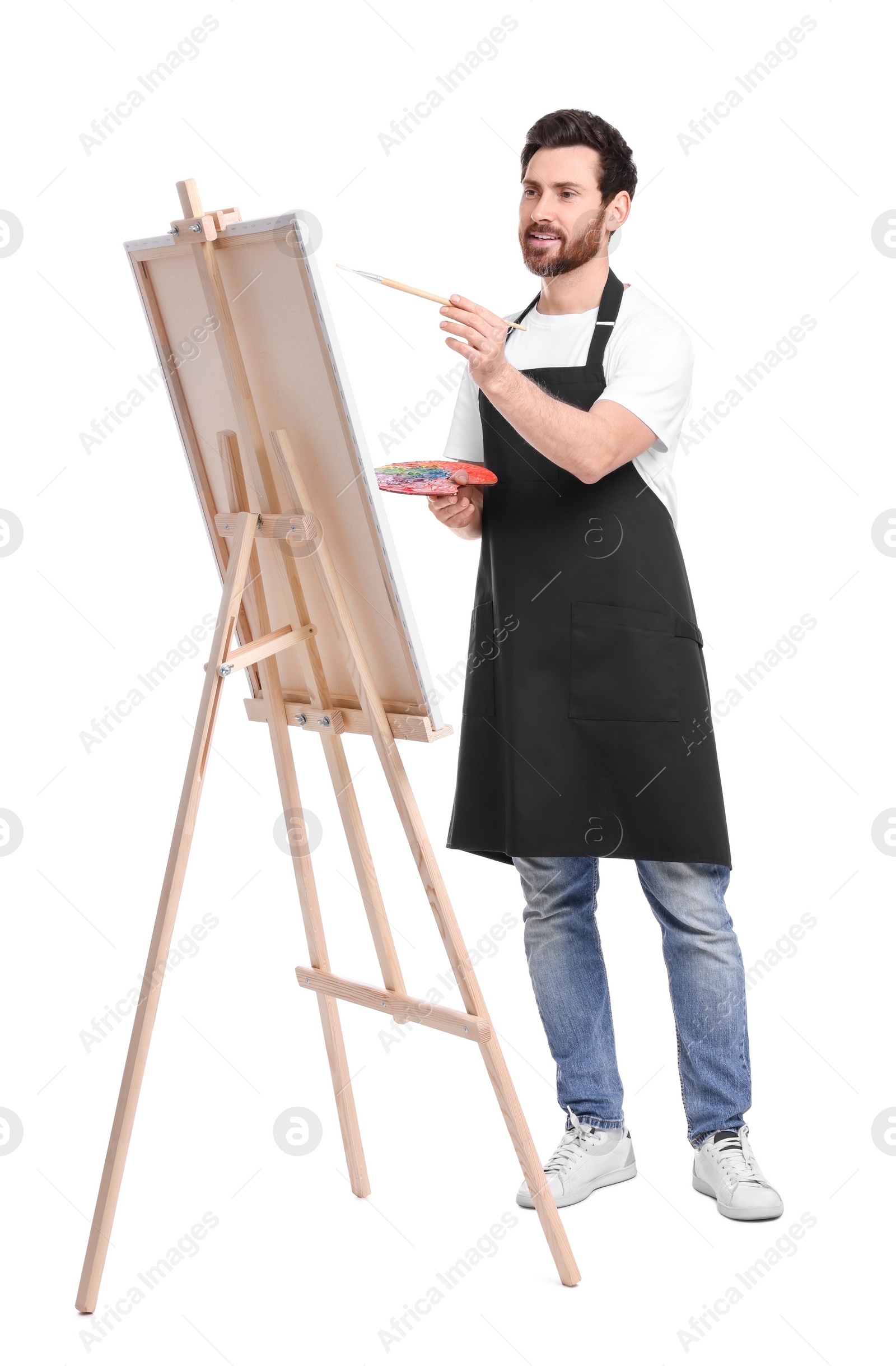 Photo of Artist with brush painting against white background. Using easel to hold canvas